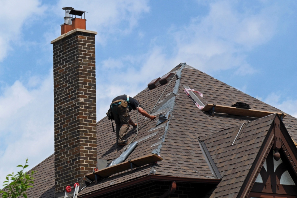 Worker replacing roof shingles